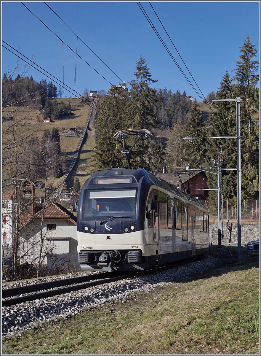 Der MOB Be 4/4 9204  Alpina  ist bie Les Avants mit einem Regionalzug auf dem Weg von Montreux nach Zweisimmen. Im Hintergrund links im Bild ist die Trasse der Standseilbahn Les Avant Sonloup zu erkennen. 

28. Jan. 2024