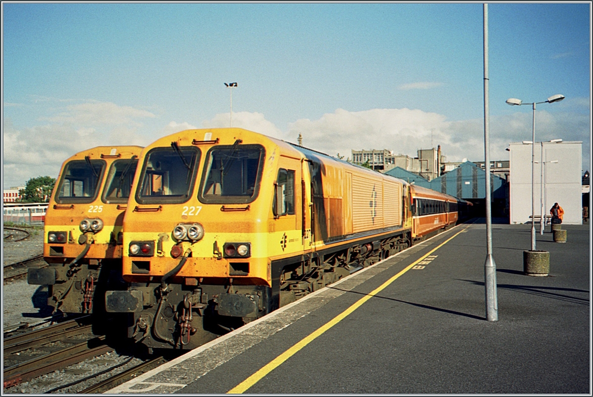 In Galway im Bahnhof Ceannt Station Galway / Stásiún Uí Ceannt steht die CIE (Iarnród Éireann) Diesel Lokomotive CC 227 und dahinter versteckt die CC 225. Das Bild zeig sehr eindrücklich, wie eng das irische Lichtraumprofil ist. 

Analog Bild vom Juni 2001