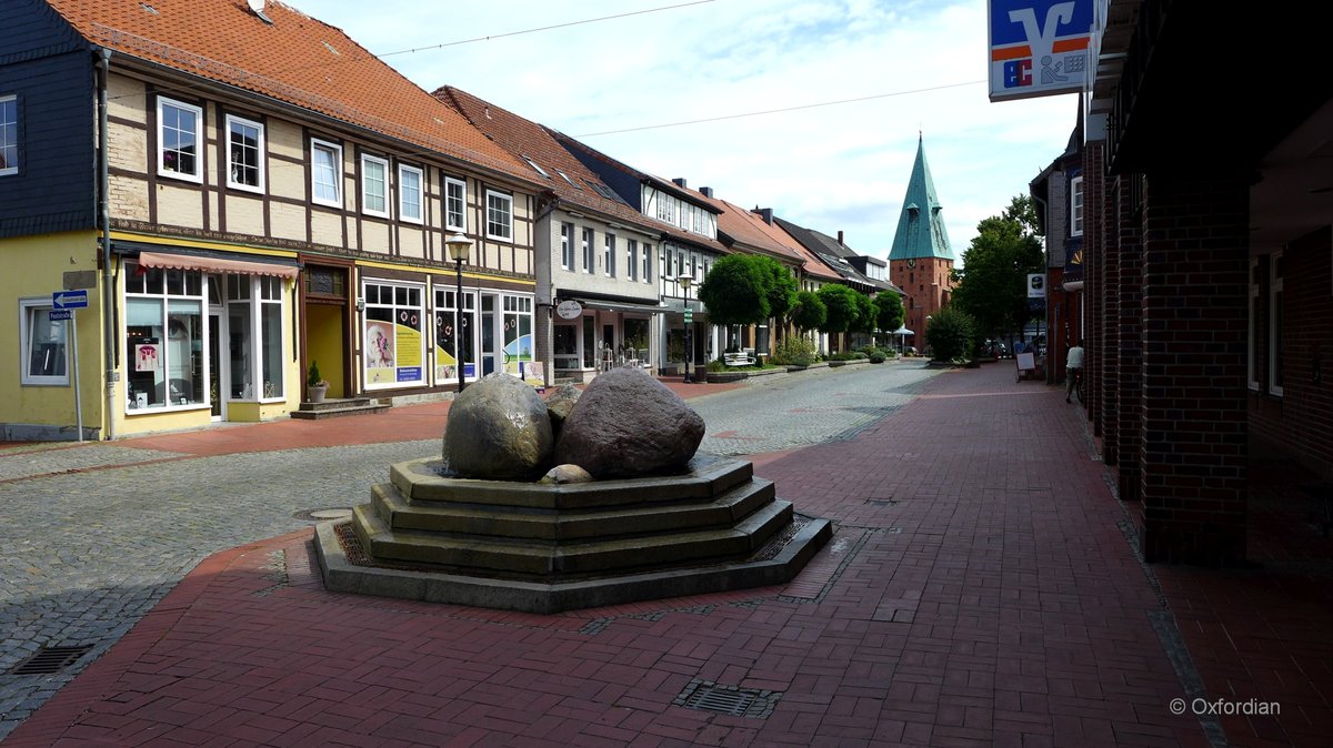 Wittingen im Landkreis Gifhorn. Lange Straße mit Brunnen und Kirchtum St. Stephanus im Bildhintergrund. 