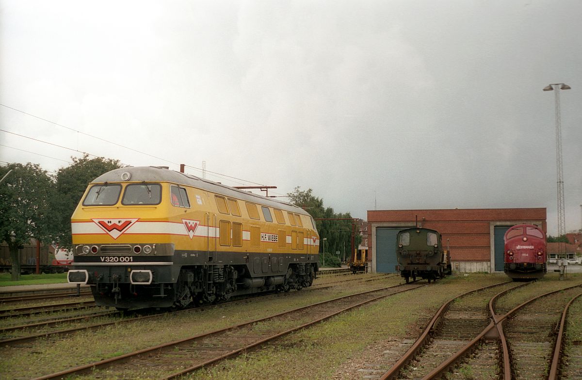 An dem ber�hmt-ber�chtigten 11. September 2001 weilte die HFW V 320 001 zu Bauarbeiten in Pattburg/Padborg, hier vor der G�terhalle zusammen mit einer K�f auf einem Transportwagen und der VESTBANEN MY 1154
