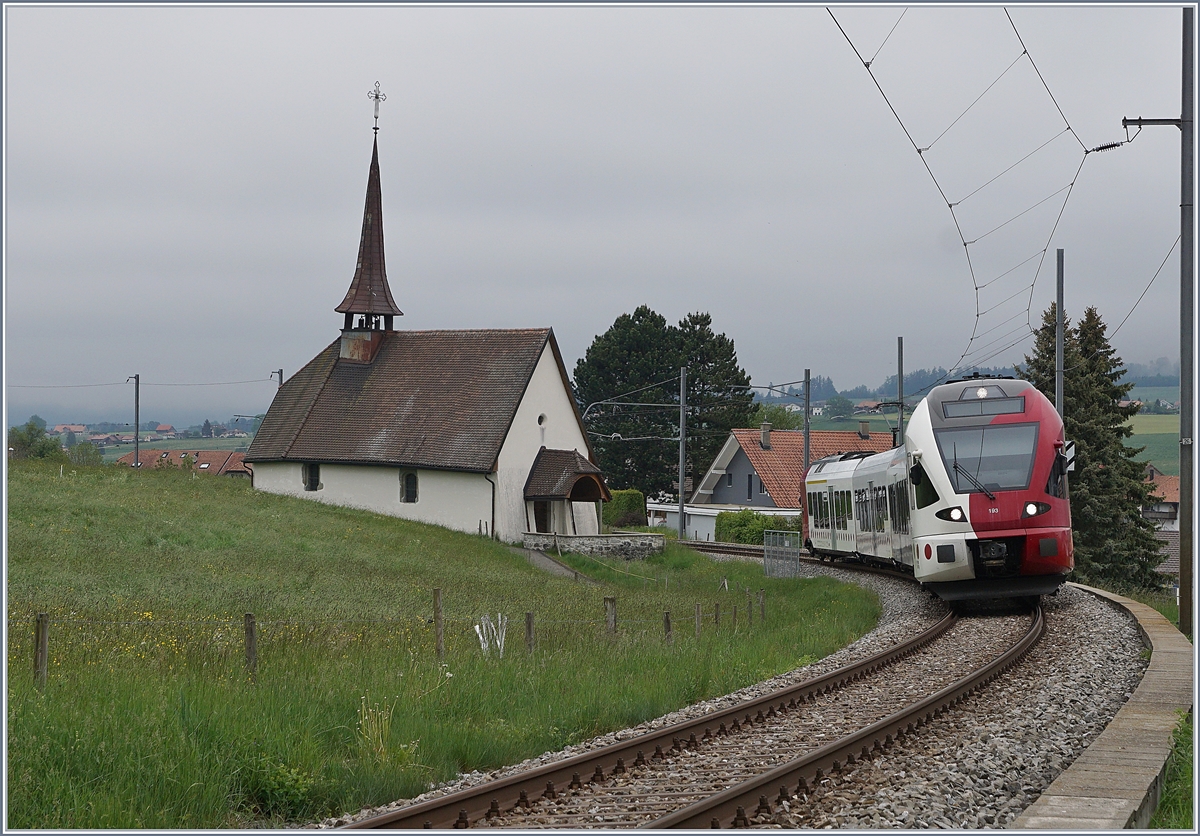 Der TPF RABe 527 193 als RE von Bulle nach Fribourg bei der  Chappel de Vaulruz  unter der herrlichen  windschiefen  Fahrleitung. 

12. Mai 2020 