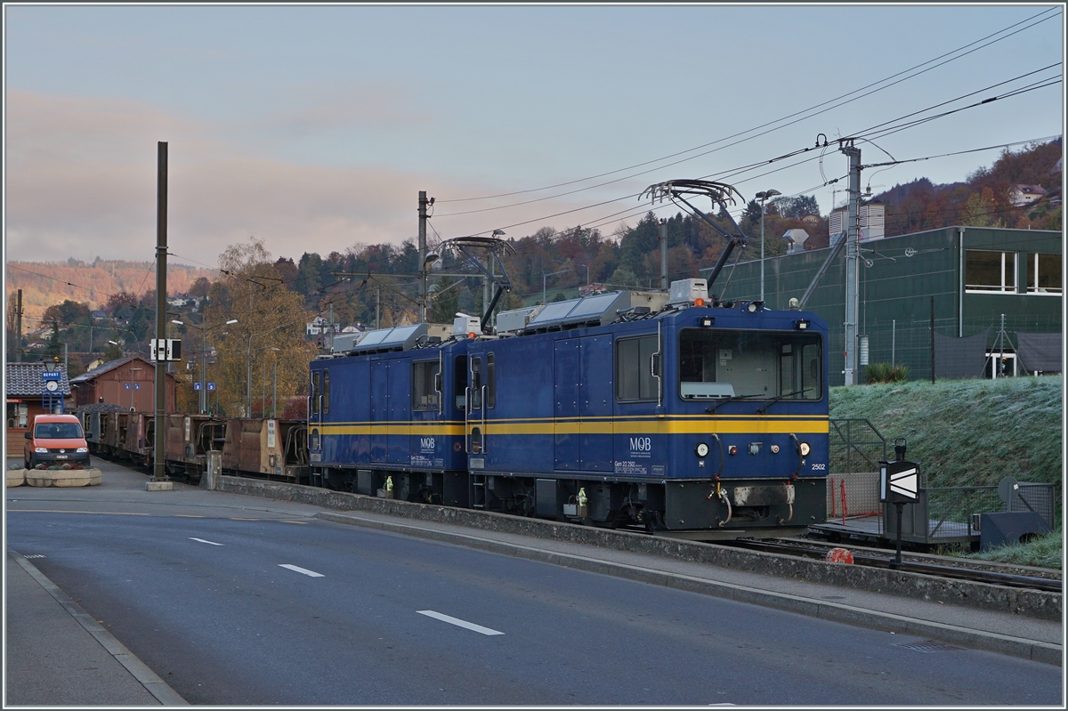 Die beiden MOB Gem 2/2 2502 und 2504 warten mit einem leeren Schotterwagenzug in Blonay auf die Abfahrt nach Chamby. 

9. November 2021