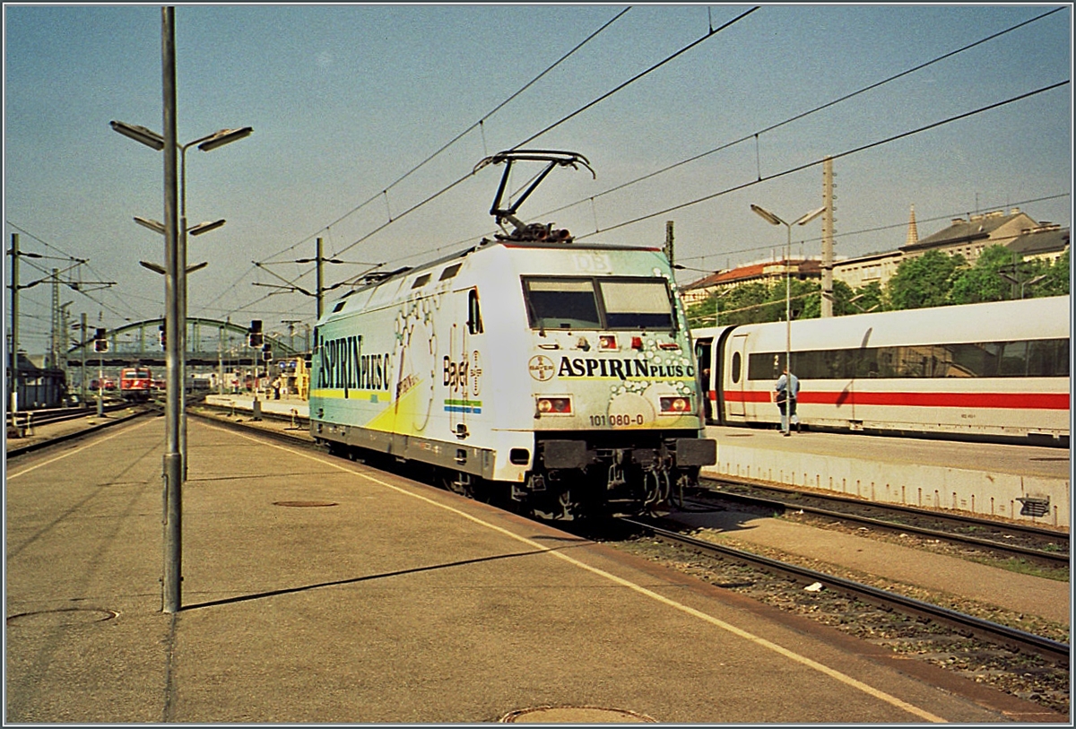 Die DB 101 080 wirbt in Wien Westbahnhof farbenfroh für  Aspirin C-Plus . 

Analogbild vom l. Mai 2001