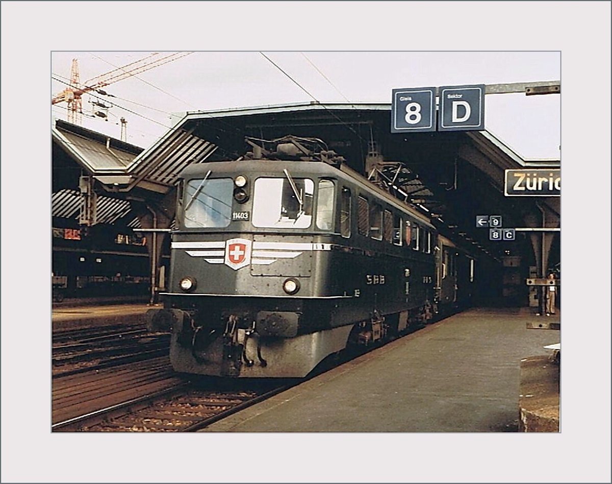 Die SBB Ae 6/6 11403  Schwyz  wartet in Zürich HB mit einem Regionalzug auf die Abfahrt. 
Die Ae 6/6 11403 war nach den beiden Prototypen Ae 6/6 11401 (Ticino) und 11402 (Uri) die erste Serien-Lok der 120 Maschinen umfassenden Baureihe Ae 6/6. 

Analogbild vom September 1984