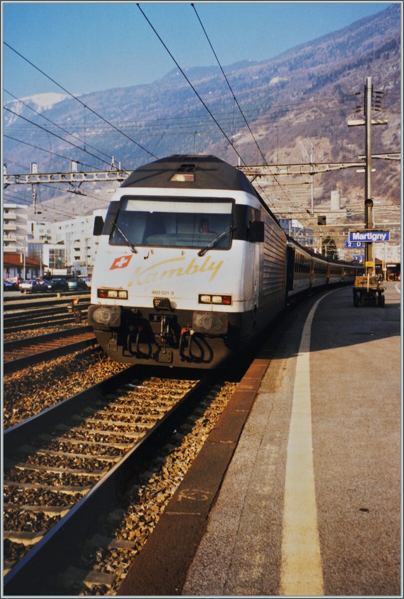 Die SBB Re 460 021-9  Kambly  beim Halt mit ihrem Schnellzug 1702 welcher auf dem Weg von Delémont nach Brig ist. 

Analogbild vom März 1998