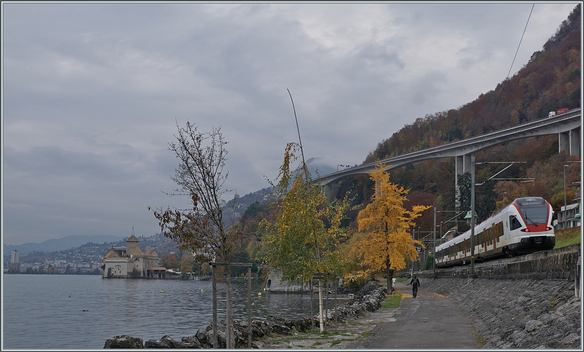 Ein SBB Flirt ist an einem düsteren Herbsttag auf der Fahrt in Richtung Lausanne und wird bald am Schloss von Chillon vorbeifahren. 

3. Nov. 2020