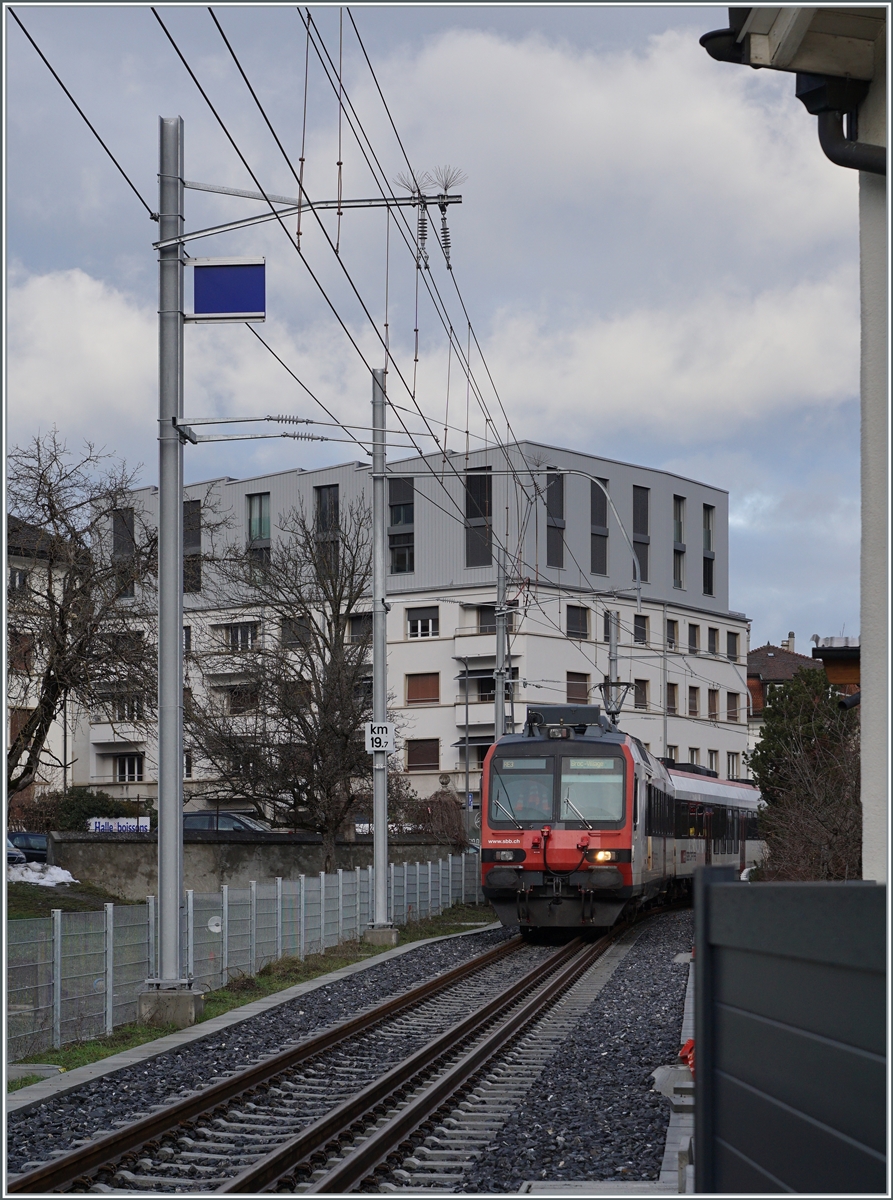 Erneut ist ein Normalspurzug auf dem Weg nach Broc, diesmal ein SBB RBDe 560  Domino  als RER 4014 von Düdingen nach Broc. Die Aufnahme entstand bei Bahnübergang der Rue du Moléson. 

22. Dezember 2022