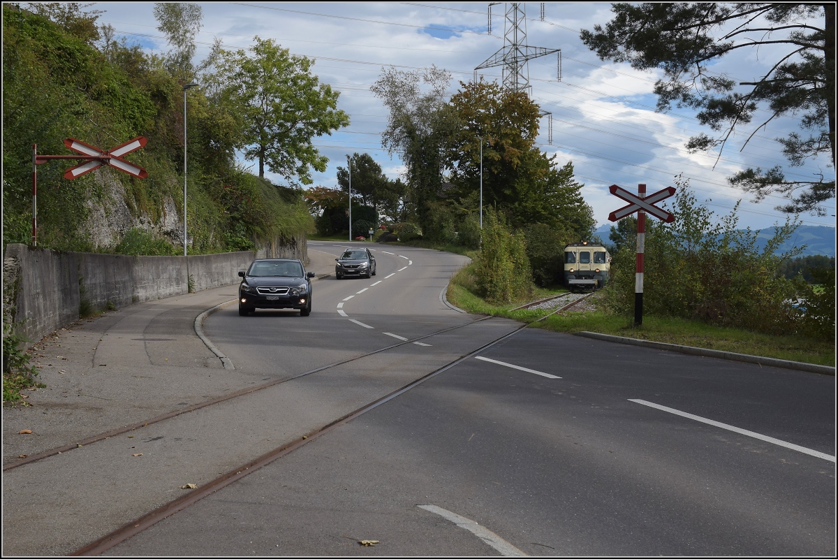 Fahrtag Wolfhuuser Bahn.

Passage des Bahnübergangs am Ortsende Wolfhausen, vorne der ABt der IG Stammgleis Wolfhausen–Bubikon. Oktober 2021.