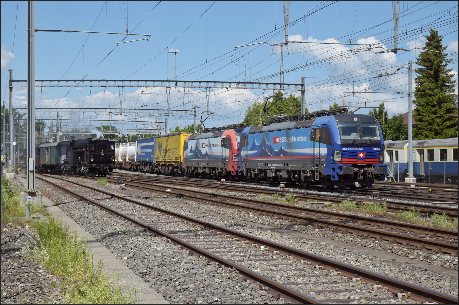 150 Jahre Emmentalbahn.

W�hrend nebenan 193 526 'Maas' und 193 475 'Domodossola' der SBB Cargo international einen G�terzug Richtung Basel bef�rdern, treffen parallel die ersehnten E 3/3 853 der Jura-Simplon und Jubil�ums-Star Ed 3/3 3 'Langnau' der Emmentalbahn mit ihrem Sonderzug im Bahnhof Burgdorf ein. Mai 2025.

Ich weiss zwar nicht ob man wegen der Paralleleinfahrt der �ltesten und neuesten Loks lachen soll oder wegen des unpassenden Hintergrunds weinen soll, aber die Freude �ber diese Begegnung mit der Lok in biblischen Alter konnte es nicht tr�ben.