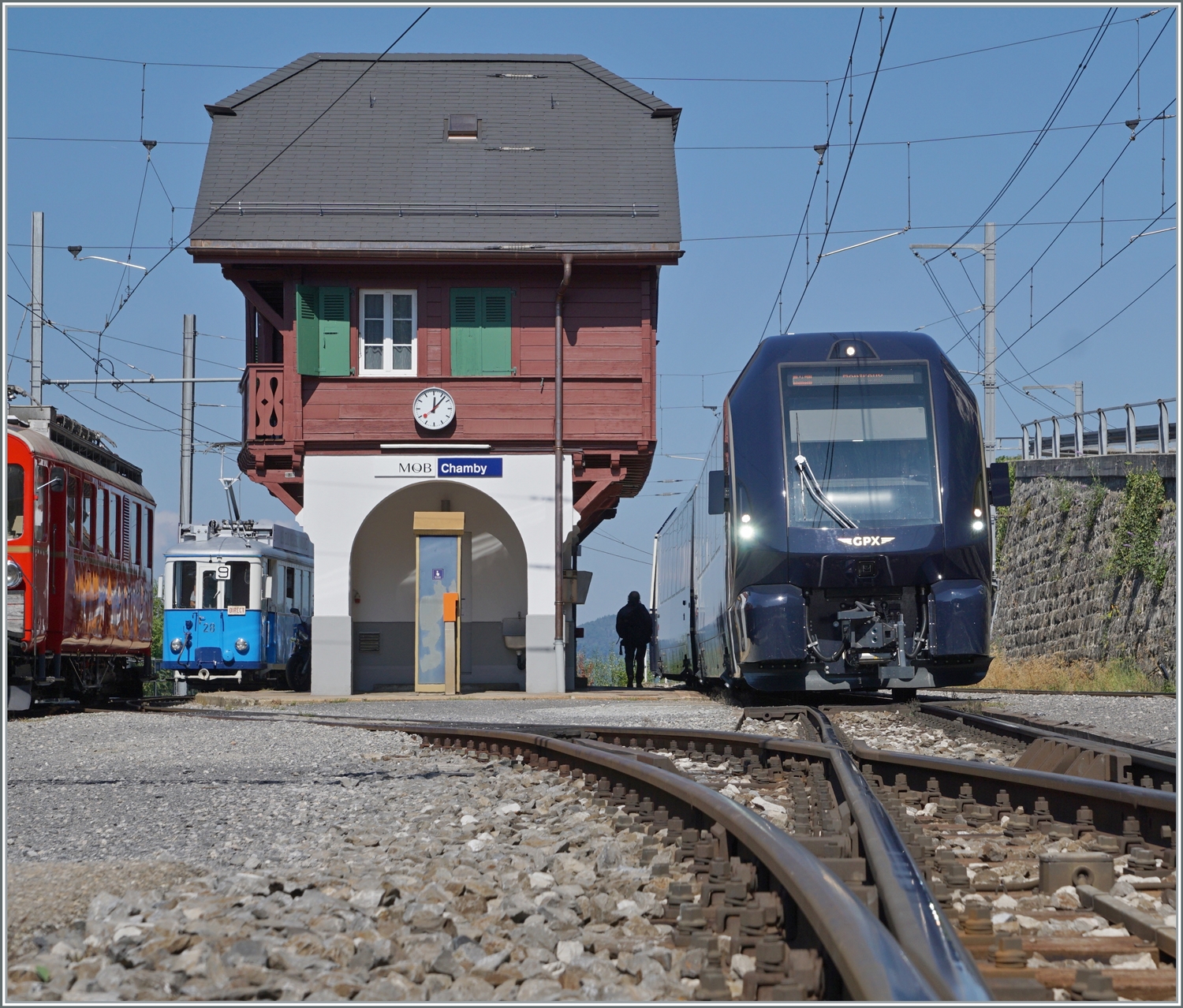 Da der GoldenPass Express von Interlaken Ost nach Montreux in Chamby auf den Gegenzug wartet, ist die Schranke beim Bahnübergang noch geöffnet und somit bietet der Übergang diese Sicht auf den GPX 4065. 

9. Sept. 2023