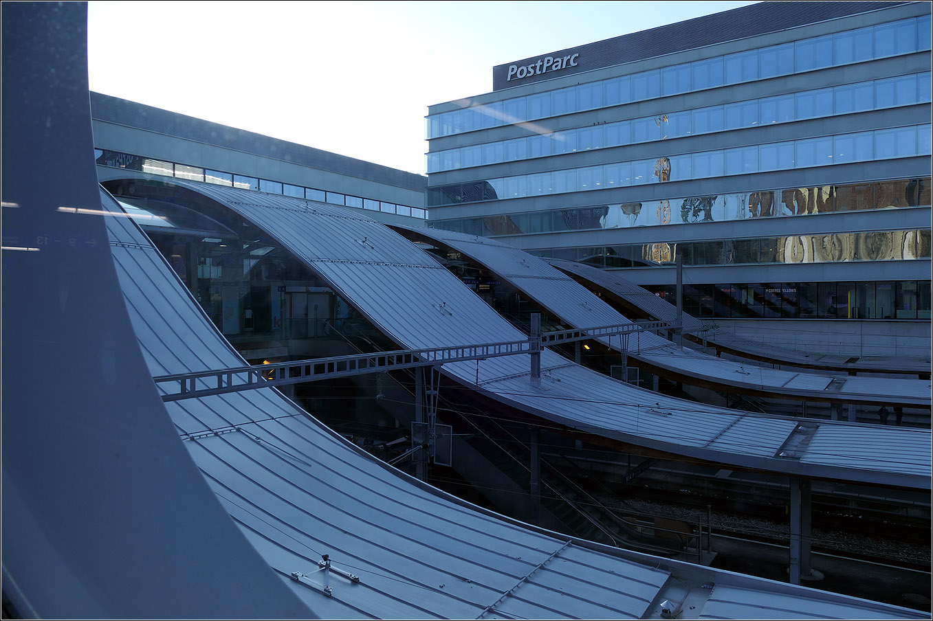 Der Bahnhof Bern - 

Im blauen Licht erscheinen die wellenförmigen Bahnsteigdächern und der Hochbau des PostParc beim Durchblick durch eines der gläsernen Bullaugen der Fahrgastbrücke zu Gleis 49 und 50.

07.03.2025