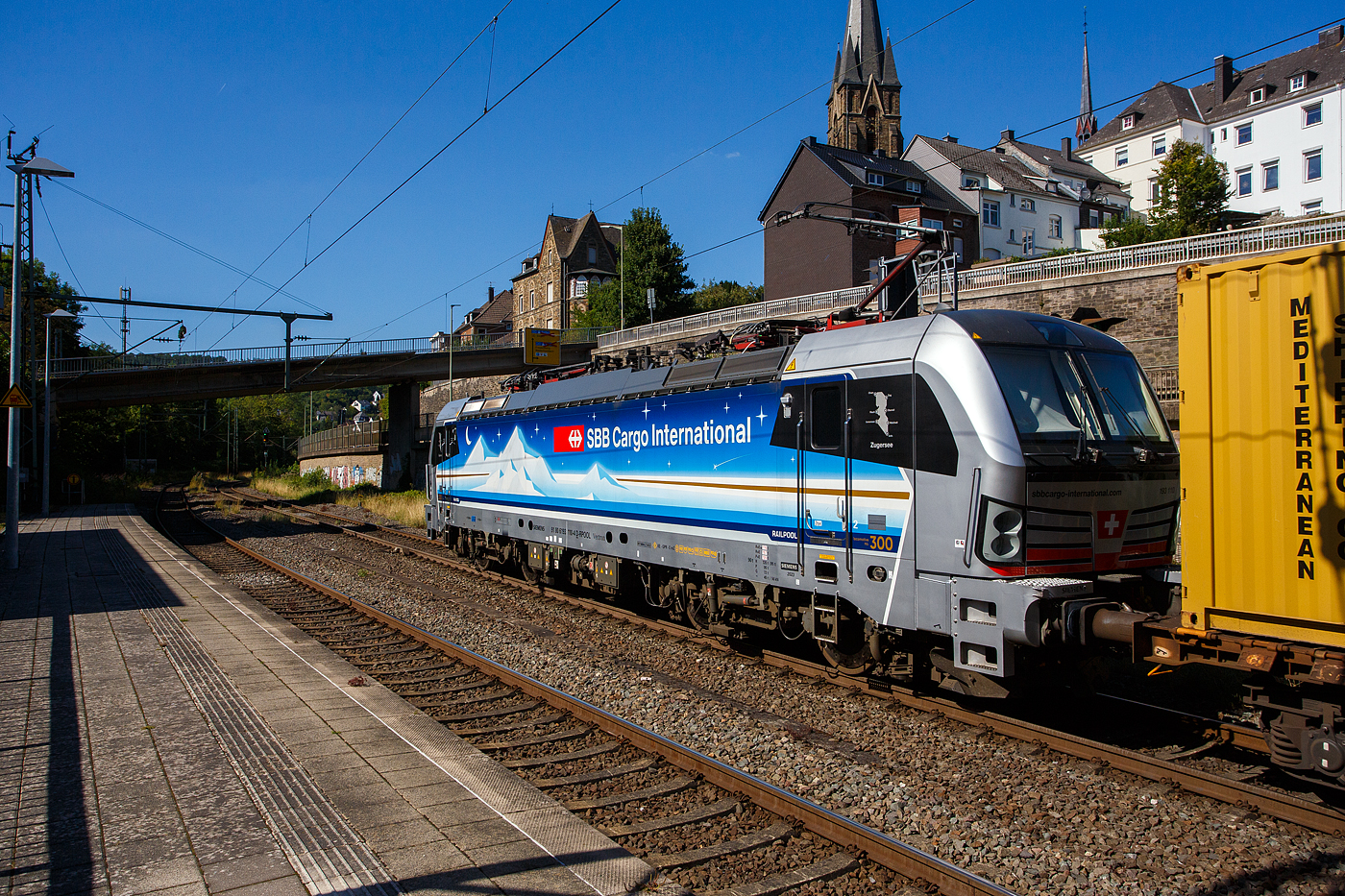 Die an die SBB Cargo International AG vermietete Siemens Vectron MS - 193 110  Zugersee  (91 80 6193 110-4 D-Rpool) der Railpool GmbH (München) fährt am 18 August 2025 mit einem Containerzug durch den Bahnhof Kirchen/Sieg in Richtung Siegen. 

Die SIEMENS Vectron MS (X4E) wurde 2023 von Siemens Mobility in München-Allach unter der Fabriknummer 23293 gebaut. Die mit 6.400 kW konzipierte Mehrsystemlok ist in der Variante A22 ausgeführt und hat so die und hat so die Zulassungen und entspr. Länderpakete für Deutschland, Österreich, Schweiz, Italien und die Niederlande (D / A / CH / I / NL), wobei z.Z. CH und I noch durchgestrichen sind. Sie ist die 300th Lokomotive der Railpool. 