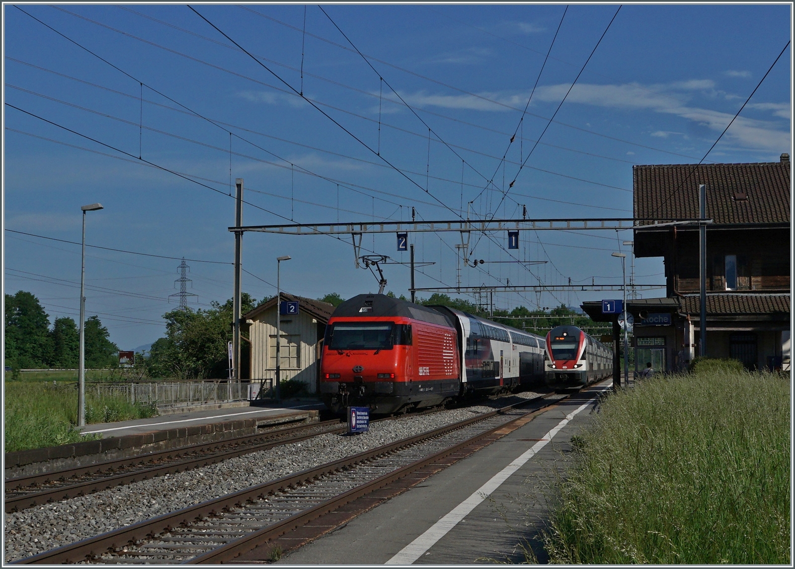 Eine SBB RE 460 mit ihrem IR 90 auf der Fahrt nach Genève und ein SBB RABe 511 aus der Gegenrichtung in Roches VD. 

12. Mai 2022