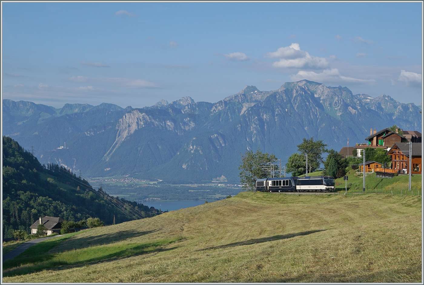 Mit Blick auf Walliser und Savoyer Alpen sowie den Genfersee als Bildhintergrund, erscheint die MOB Ge 4/4 8002 mit dem Golden Pass Express GEX 4064 von Montreux nach Interlaken Ost bei Les Avants. In Zweisimmen wird eine BLS Re 465 die MOB ge 4/4 8002 ablösen. 

28. Juni 2024