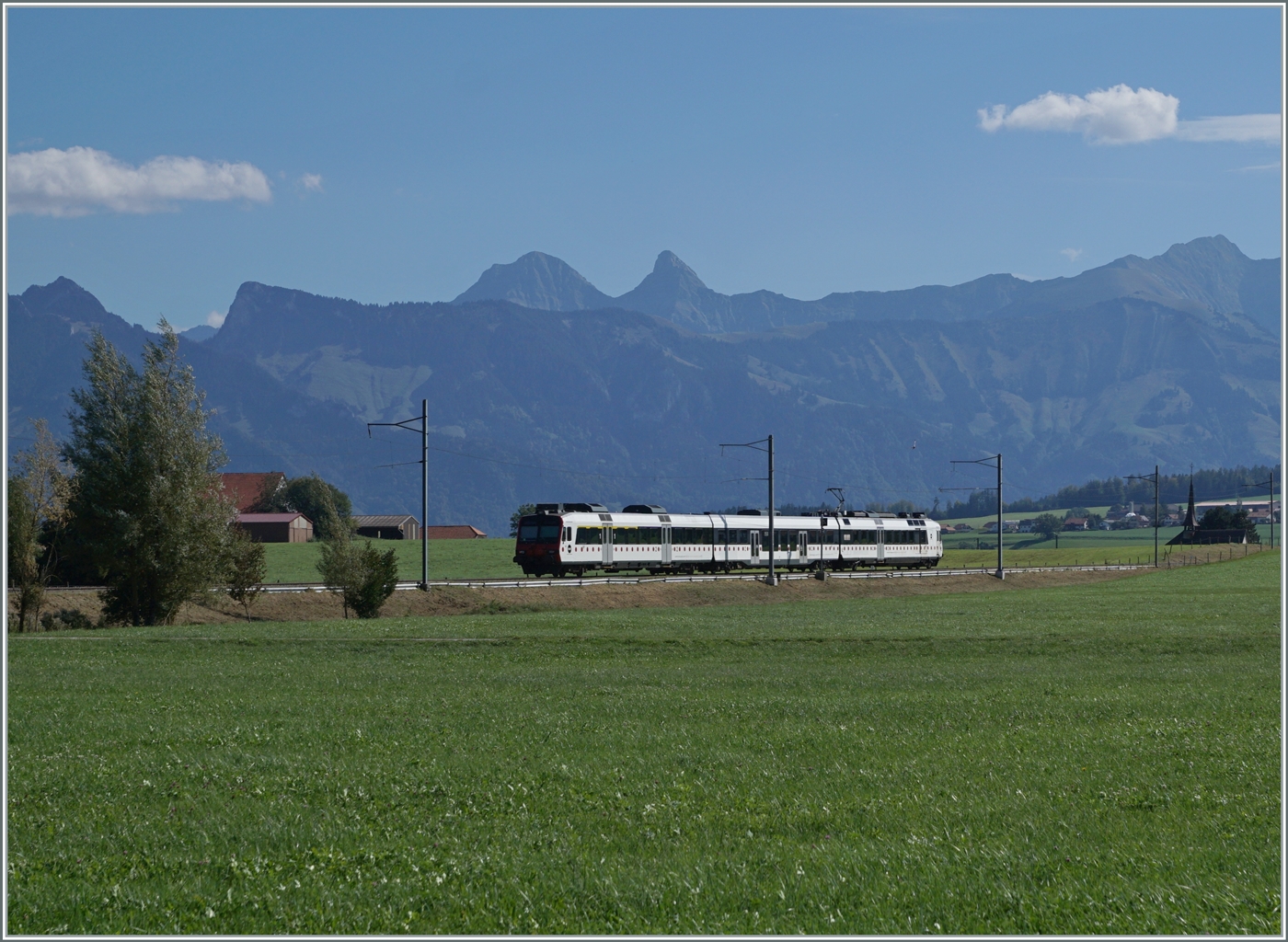 Zwischen Sâles und Vaulruz ist ein TPF RBDe 560 Domino auf dem Weg nach Broc Fabrique. 
Im Hintergrund die Freiburger Alpen. 

29. Sept. 2023